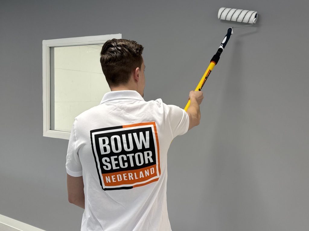 Vakman van Bouwsector Nederland rolt de bovenrand van een grijze wand